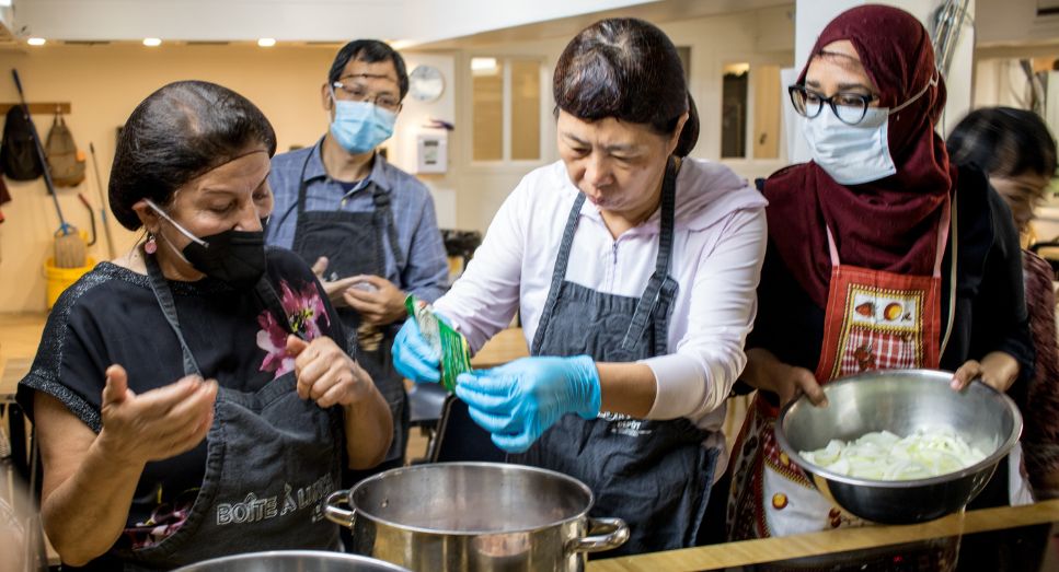 four people with masks on cooking