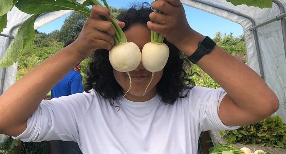 woman holding turnips in front of face